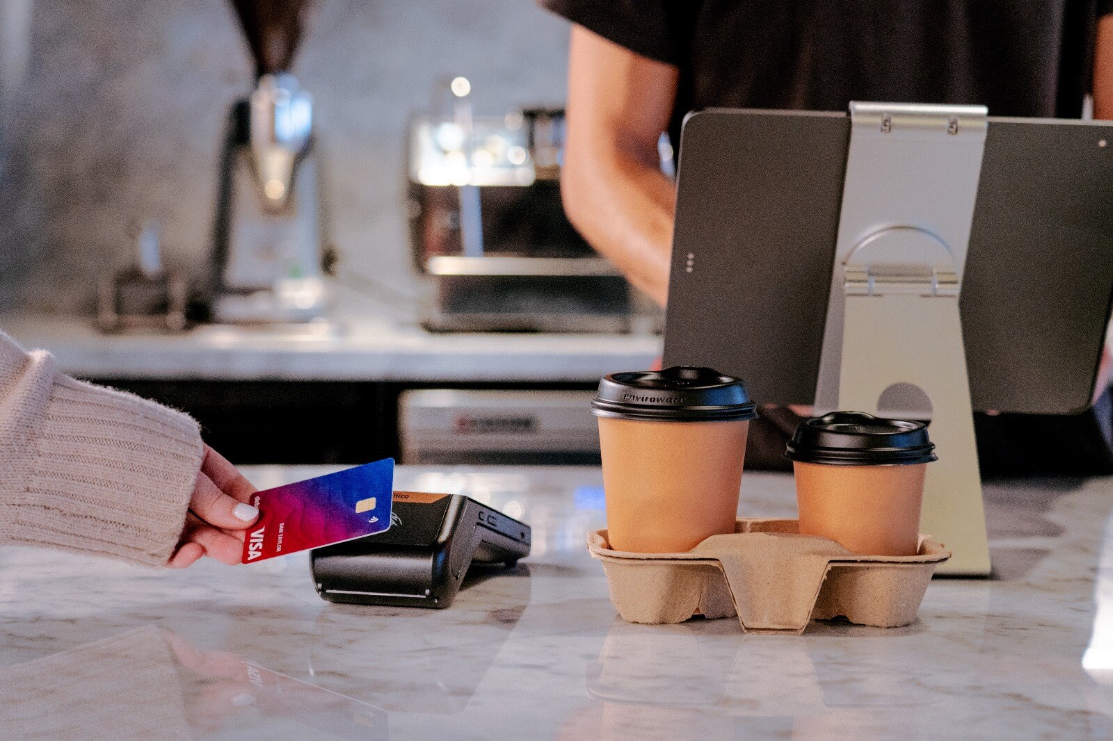 Card payment on a Kokipay EFTPOS terminal at a cafe counter beside takeaway coffees